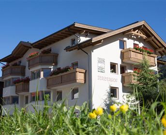 A charming building with balconies and blooming plants. The sky is clear and blue, creating an inviting atmosphere.