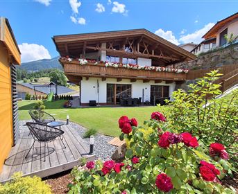 Ein modernes Haus mit einem großen Garten und einem Balkon. Bunte Blumen und eine schöne Landschaft umgeben die Unterkunft.