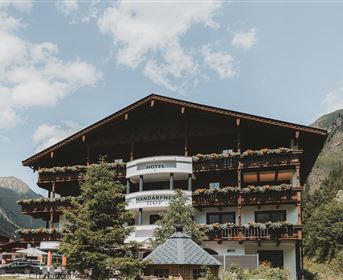 Ein charmantes Hotel in den Bergen mit einem traditionellen alpinen Design. Umgeben von Bäumen und Bergen, strahlt es eine gemütliche Atmosphäre aus.