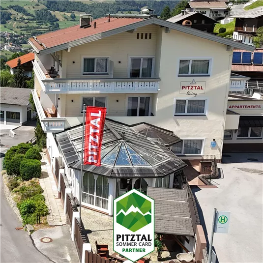 A charming building in the Pitztal with a glass veranda and a large red banner. The hotel offers an attractive view of the surrounding mountain landscape.