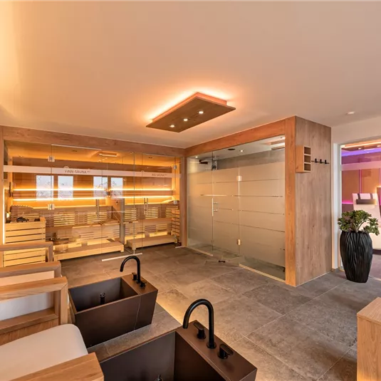 A modern spa with comfortable seating and footbaths. Soft lighting and wooden accents create a relaxing atmosphere.