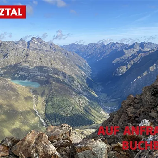 A spectacular mountain landscape in the Pitztal with high peaks and deep valleys. In the foreground are rocky foothills, and in the background, a clear sky stretches out.