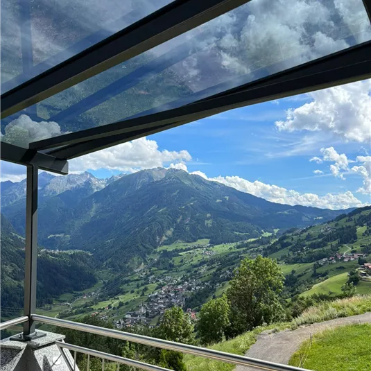 Eine schöne Aussicht auf die Berge und das Tal unter einem klaren Himmel. Der Blick zeigt eine grüne Landschaft mit einigen Wolken.