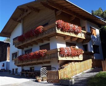 Ein traditionelles Chalet mit Holzverkleidung und Blumenbalkonen. Es liegt in einer ruhigen Umgebung mit klarem Himmel.