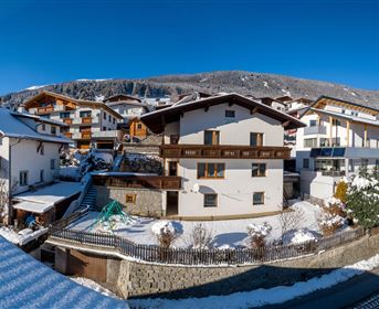 Ein malerisches winterliches Dorf mit schneebedeckten Häusern und einer klaren blauen Himmel. Die Szene strahlt eine ruhige und gemütliche Atmosphäre aus.