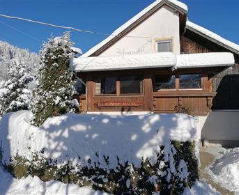 A charming wooden house in a snowy landscape. The clear blue sky accentuates the wintry atmosphere.