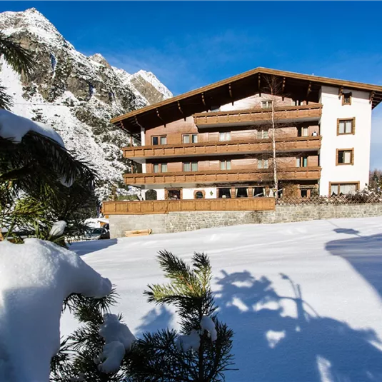 A charming hotel in the snow, surrounded by mountains. The landscape is wintry and inviting.